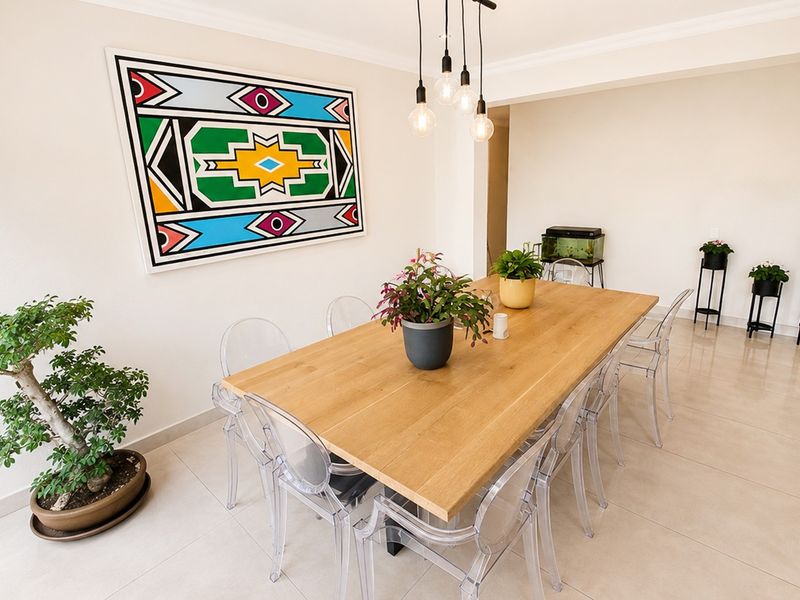 A bright and modern dining area featuring neutral tiled flooring, coved ceilings, and contemporary pendant lighting, creating a clean and inviting space.