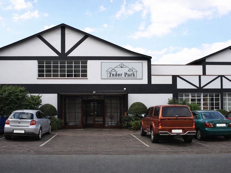 Front elevation of Tudor Park commercial building featuring a distinctive timber-framed facade, multi-pane windows, and dedicated paved parking bays.