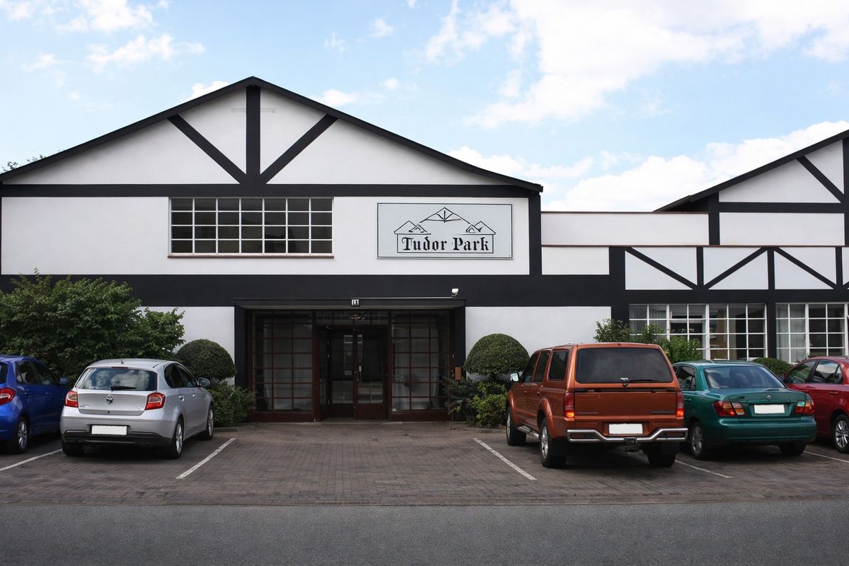 Front elevation of Tudor Park commercial building featuring a distinctive timber-framed facade, multi-pane windows, and dedicated paved parking bays.