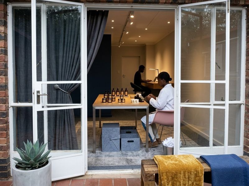 A well-lit office space viewed through double glass doors, featuring modern track lighting and recessed ceiling lights, suitable for a professional workspace.