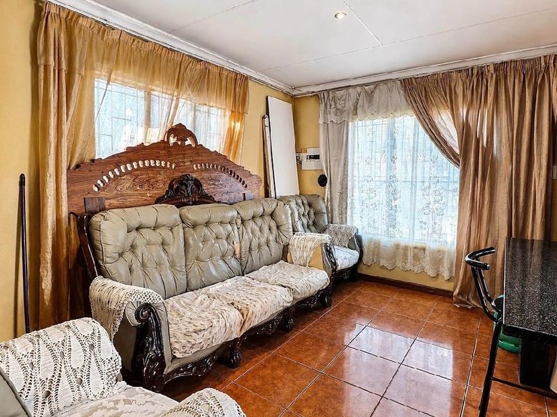 A living room featuring tiled flooring, recessed ceiling lights, and windows fitted with security bars, offering a functional space with potential for modernization.