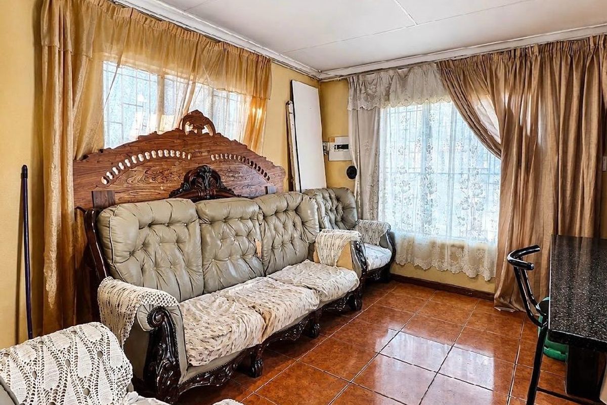 A living room featuring tiled flooring, recessed ceiling lights, and windows fitted with security bars, offering a functional space with potential for modernization.