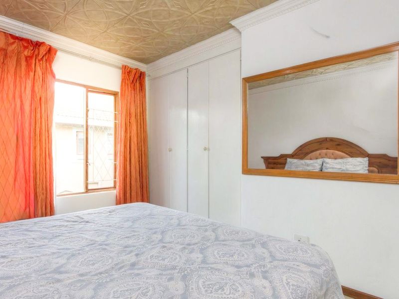 A bedroom featuring built-in cupboards, decorative textured ceiling, and cornicing, providing a functional space with classic architectural details.