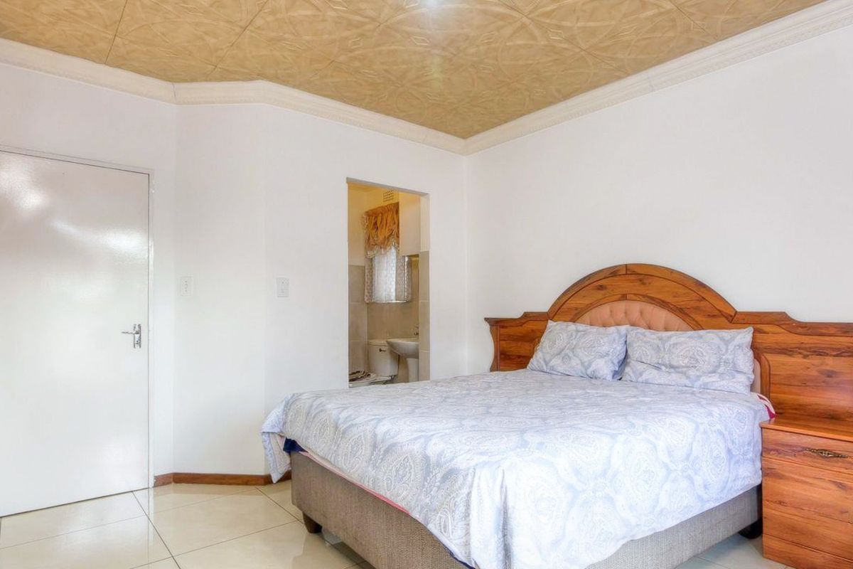 A bedroom featuring tiled flooring and a textured ceiling, with direct access to an adjoining en-suite bathroom.