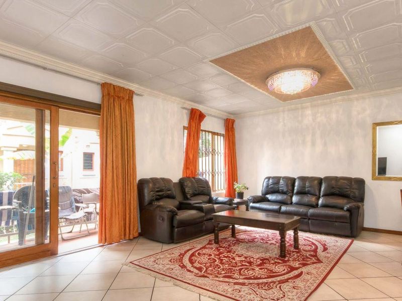 Open plan living area featuring tiled flooring, decorative ceiling tiles, and sliding glass doors providing access to the outdoor patio area.