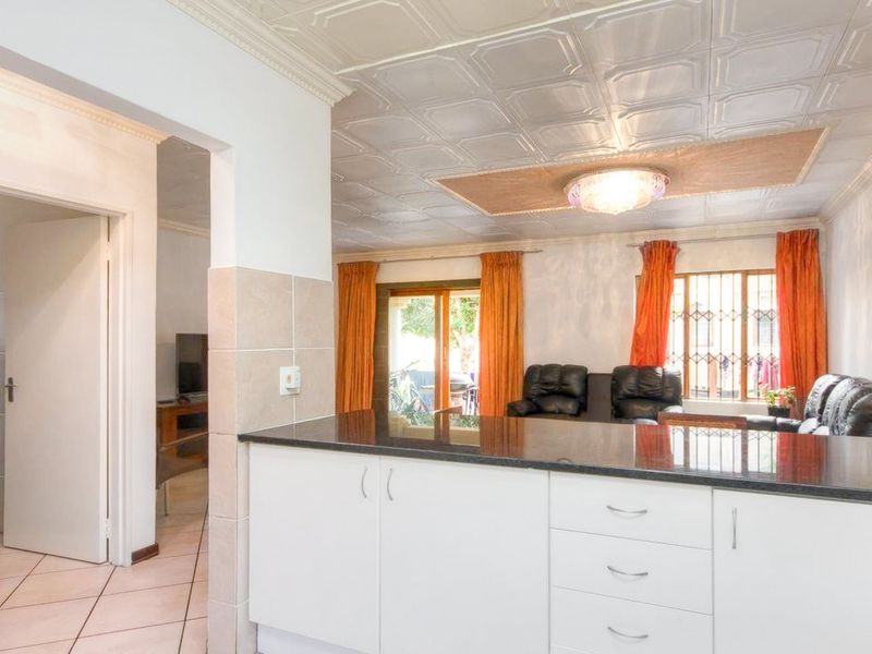 Open plan kitchen and living area featuring granite countertops, white cabinetry, tiled flooring, and decorative ceiling tiles with access to an outdoor patio.
