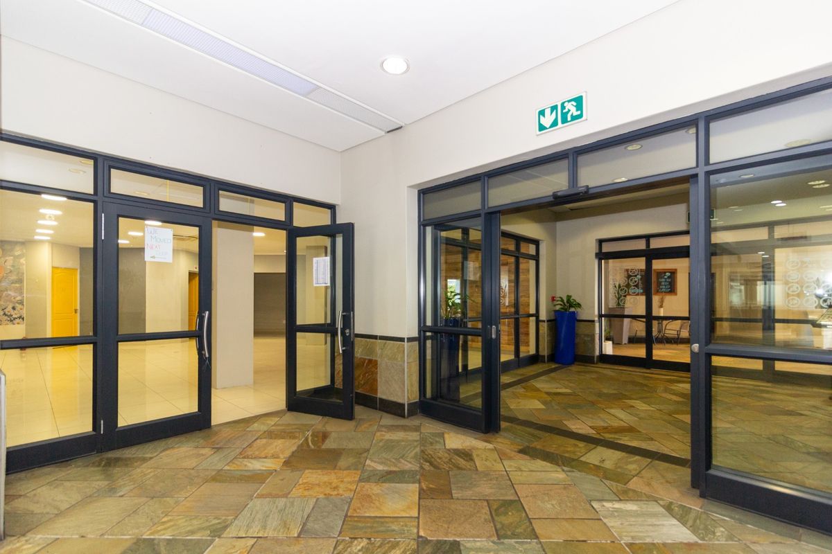 A bright and professional commercial entrance lobby featuring natural stone flooring, aluminium-framed glass doors, and recessed lighting, providing a clean and welcoming access point.
