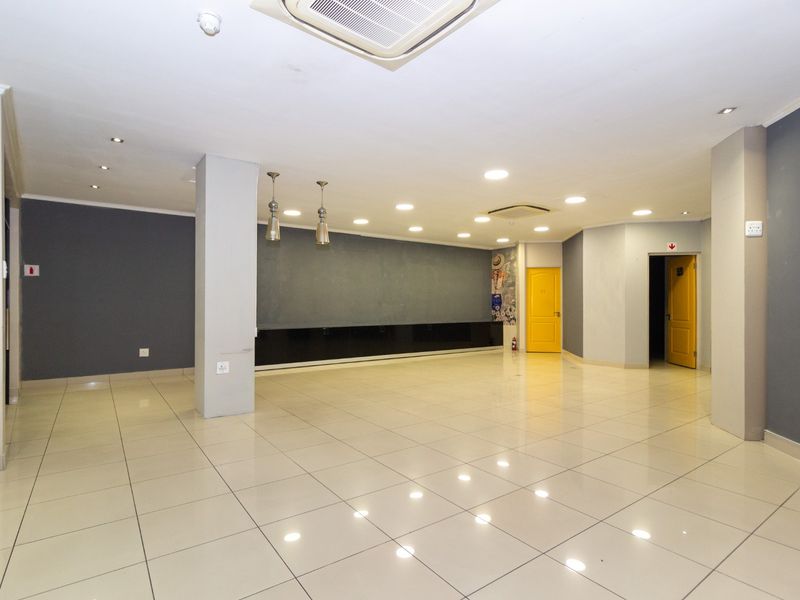 Spacious open-plan retail area featuring polished tiled flooring, recessed ceiling lighting, integrated air conditioning, and neutral grey wall finishes.