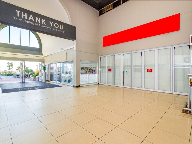 Spacious retail entrance foyer featuring tiled flooring, large glass storefront doors, and an arched window providing natural light.