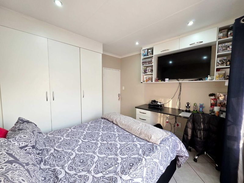 A functional bedroom featuring extensive built-in cupboards, a integrated desk with overhead storage cabinetry, and modern recessed downlighting.