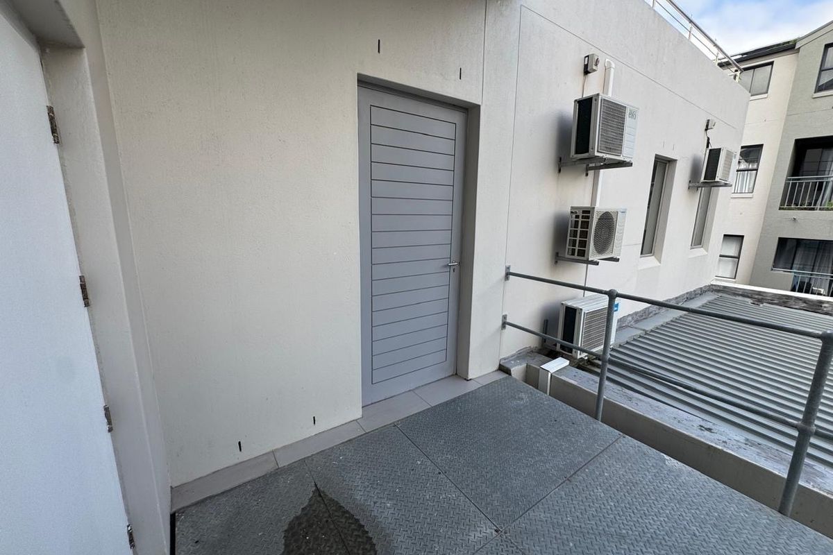 An exterior balcony area featuring metal flooring, safety railings, and wall-mounted air conditioning units.