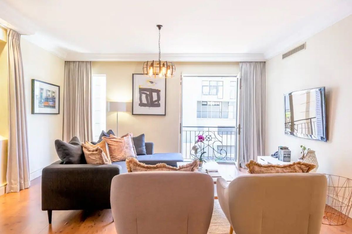 A well-maintained living room featuring hardwood flooring, decorative cove cornicing, and direct access to a private balcony through a glass door.