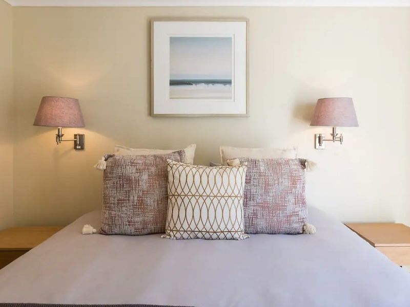 A well-maintained bedroom featuring symmetrical wall-mounted reading lights and a neutral color palette.