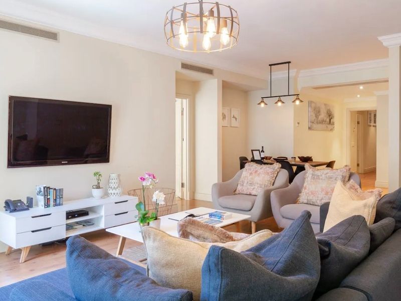 Spacious open-plan living and dining area featuring hardwood flooring, crown molding, and integrated ducted air conditioning.