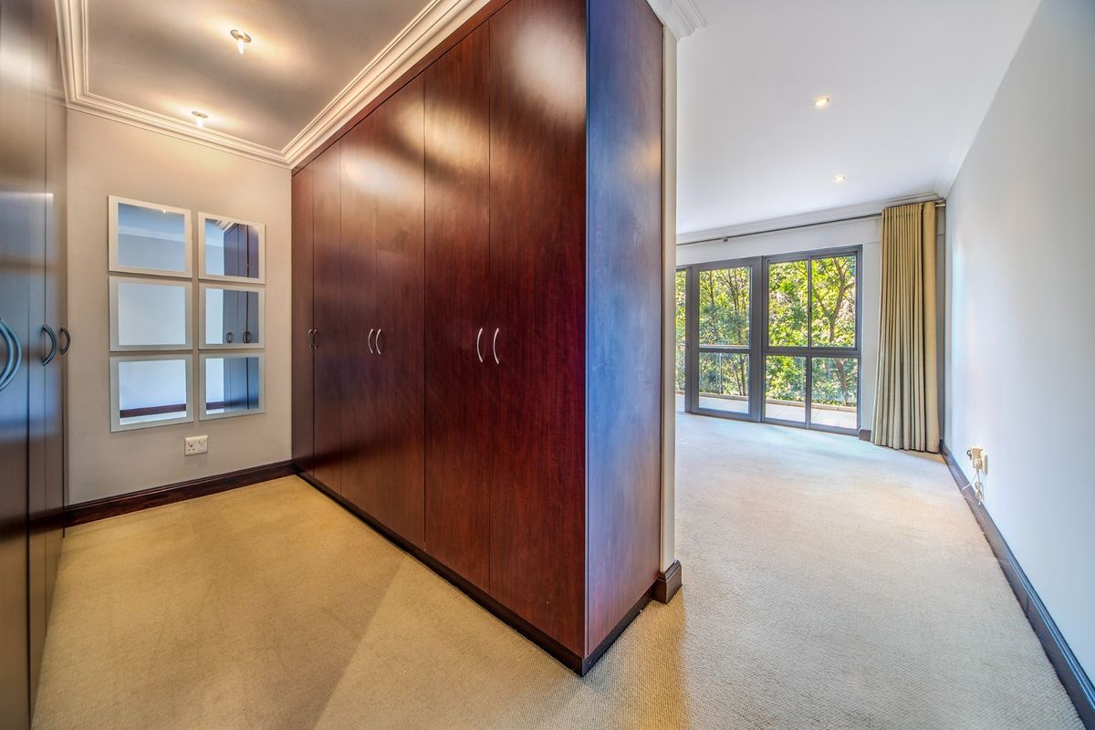 Spacious bedroom featuring extensive built-in cupboards, neutral carpeting, and large sliding glass doors that provide ample natural light and views.