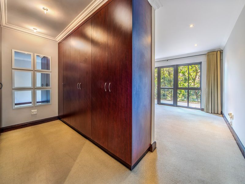 Spacious bedroom featuring extensive built-in cupboards, neutral carpeting, and large sliding glass doors that provide ample natural light and views.