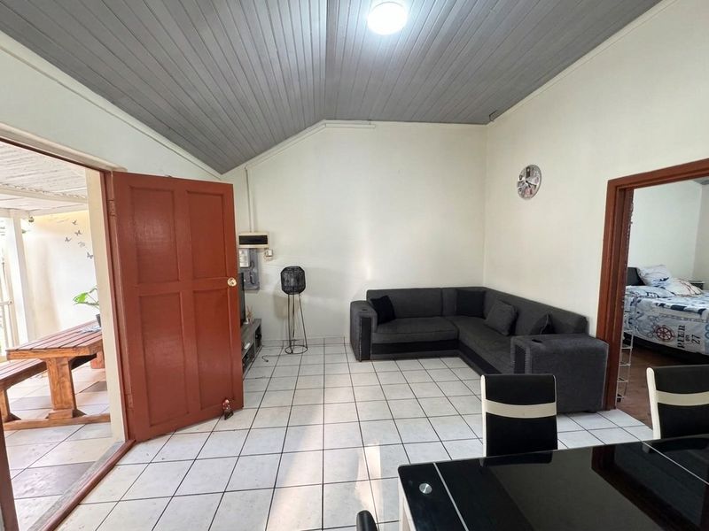 A living room featuring tiled flooring and a timber panelled ceiling, with direct access to an outdoor patio area.