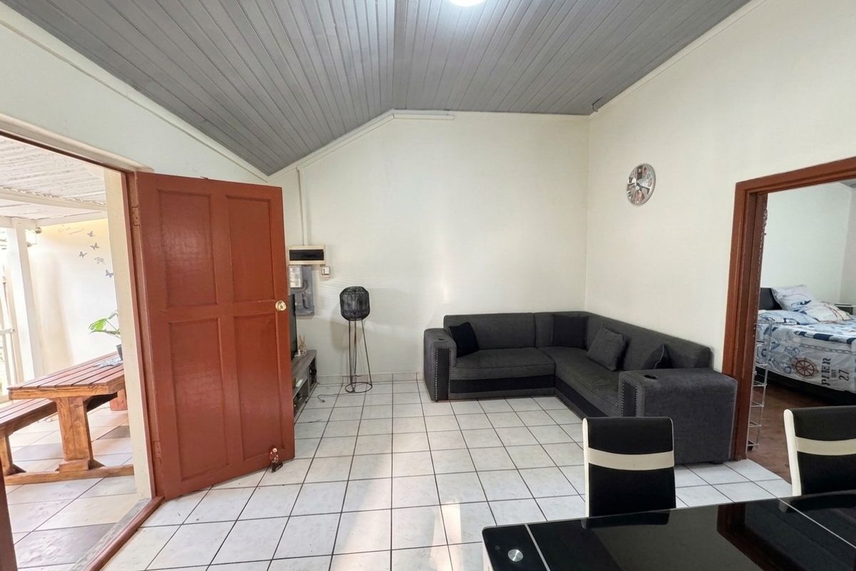 A living room featuring tiled flooring and a timber panelled ceiling, with direct access to an outdoor patio area.