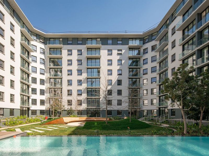 A modern multi-story residential complex featuring a central courtyard with a swimming pool, landscaped garden, and contemporary glass-balustraded balconies.