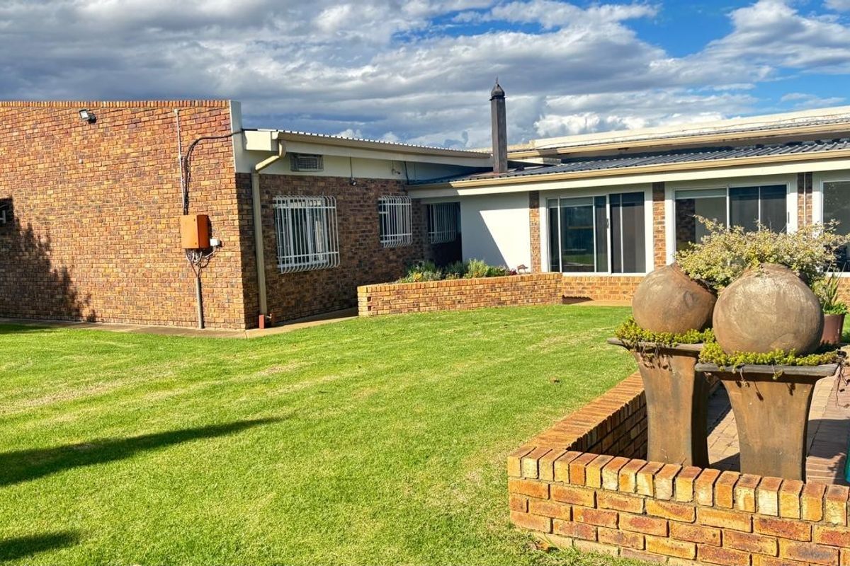 Rear view of the property featuring a face-brick facade, a well-maintained lawn, and a swimming pool with a brick-paved surround.