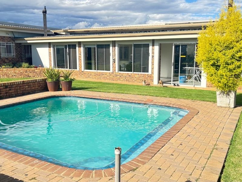 Outdoor pool area featuring a swimming pool, brick paving, and a retaining wall, with direct access to the main dwelling via sliding glass doors.