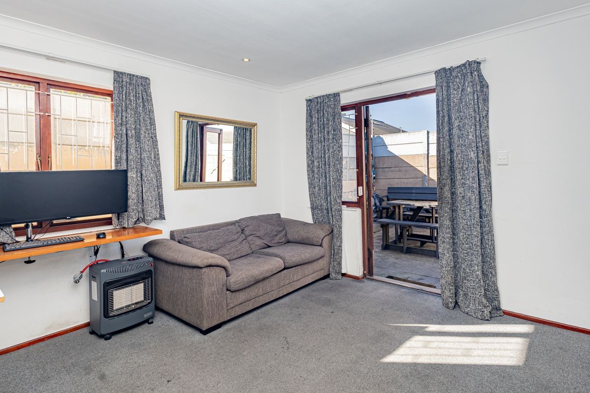 A living room featuring carpet flooring, coved ceilings, and a sliding glass door providing direct access to an outdoor patio area.