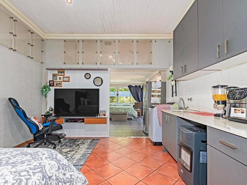 Open plan living area featuring a compact kitchenette with grey cabinetry, tiled flooring, and a high tongue and groove ceiling.