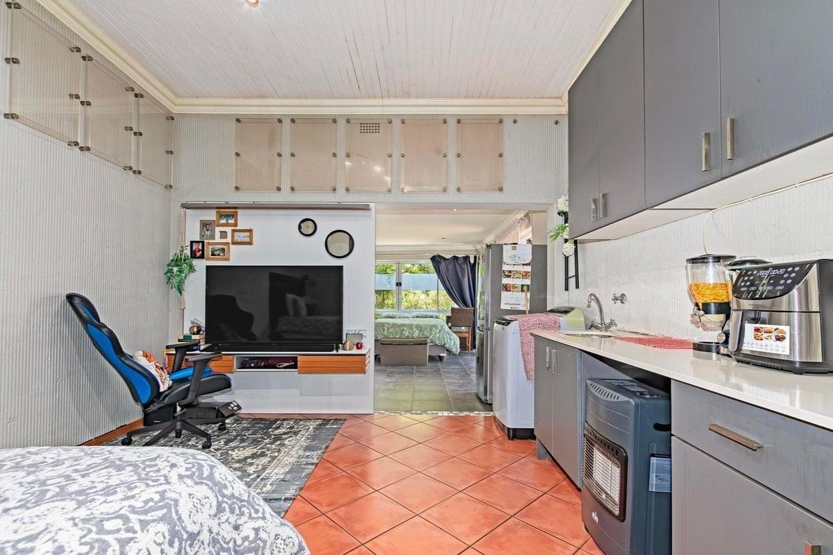 Open plan living area featuring a compact kitchenette with grey cabinetry, tiled flooring, and a high tongue and groove ceiling.