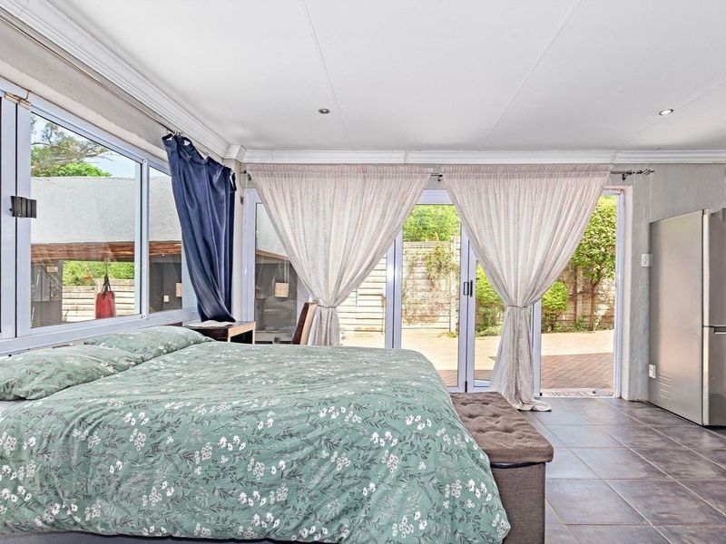 Spacious bedroom featuring tiled flooring, large windows, and sliding glass doors providing direct access to the rear patio area.