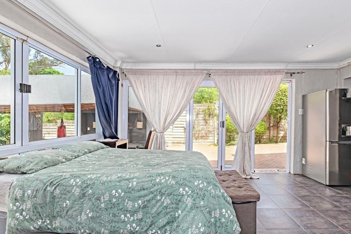 Spacious bedroom featuring tiled flooring, large windows, and sliding glass doors providing direct access to the rear patio area.