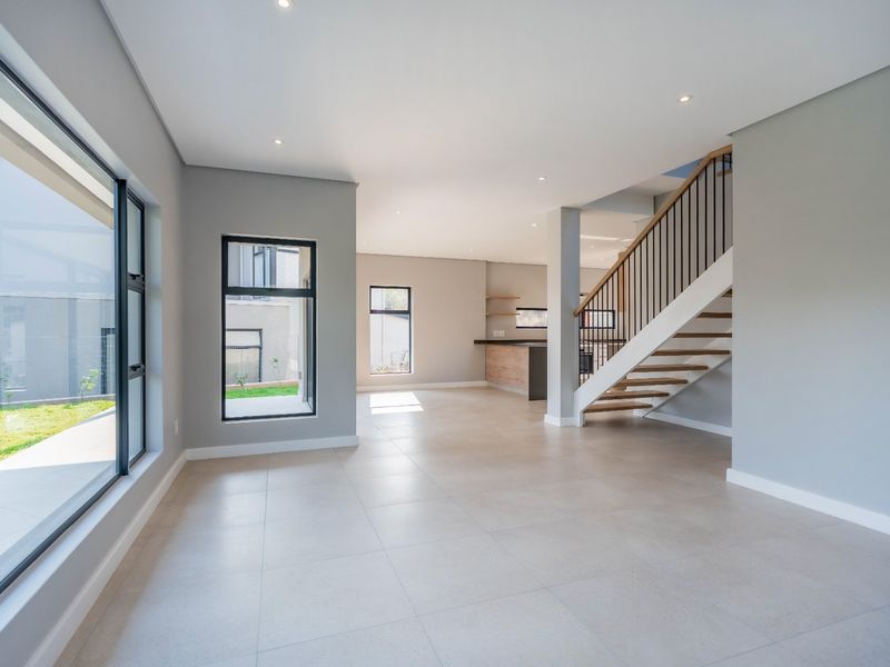Spacious open-plan living area featuring modern tiled floors, recessed lighting, large windows, and a contemporary staircase with timber treads.