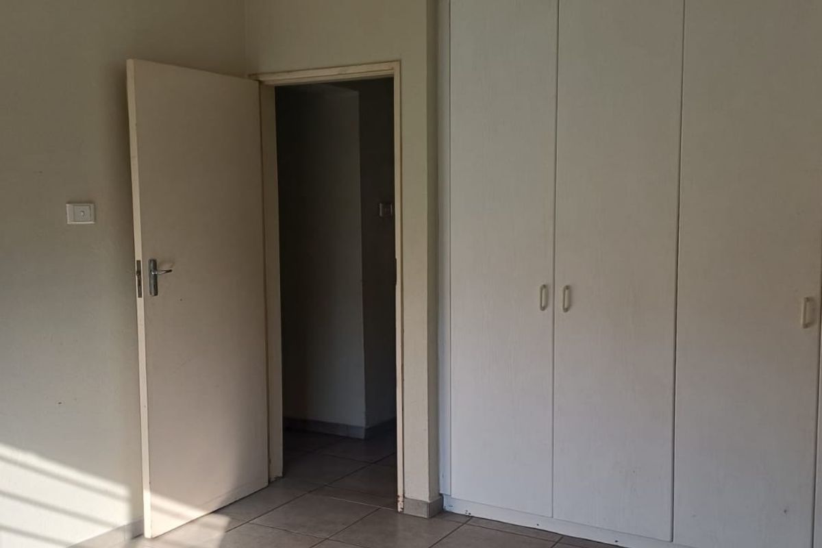 A vacant bedroom featuring tiled flooring and built-in cupboards, offering a neutral space ready for personalization.