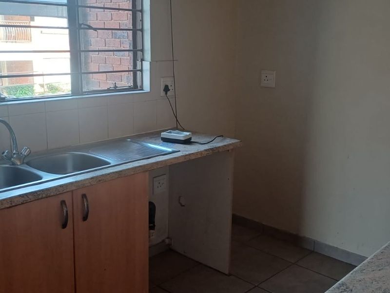 A functional kitchen area featuring a double bowl sink, laminate countertops, and built-in cabinetry, offering a blank canvas for potential renovation.