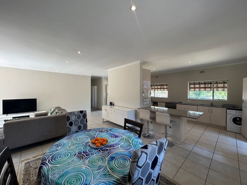 Spacious open-plan living and kitchen area featuring tiled floors, a breakfast bar, and modern cabinetry, creating a functional and connected family space.