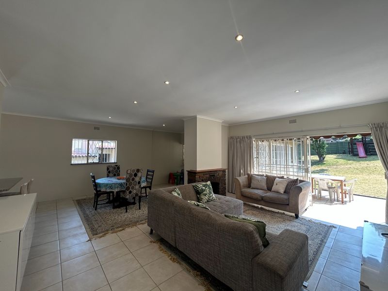 Spacious open-plan living and dining area featuring tiled floors, a central brick fireplace, and large sliding doors providing direct access to the rear garden.