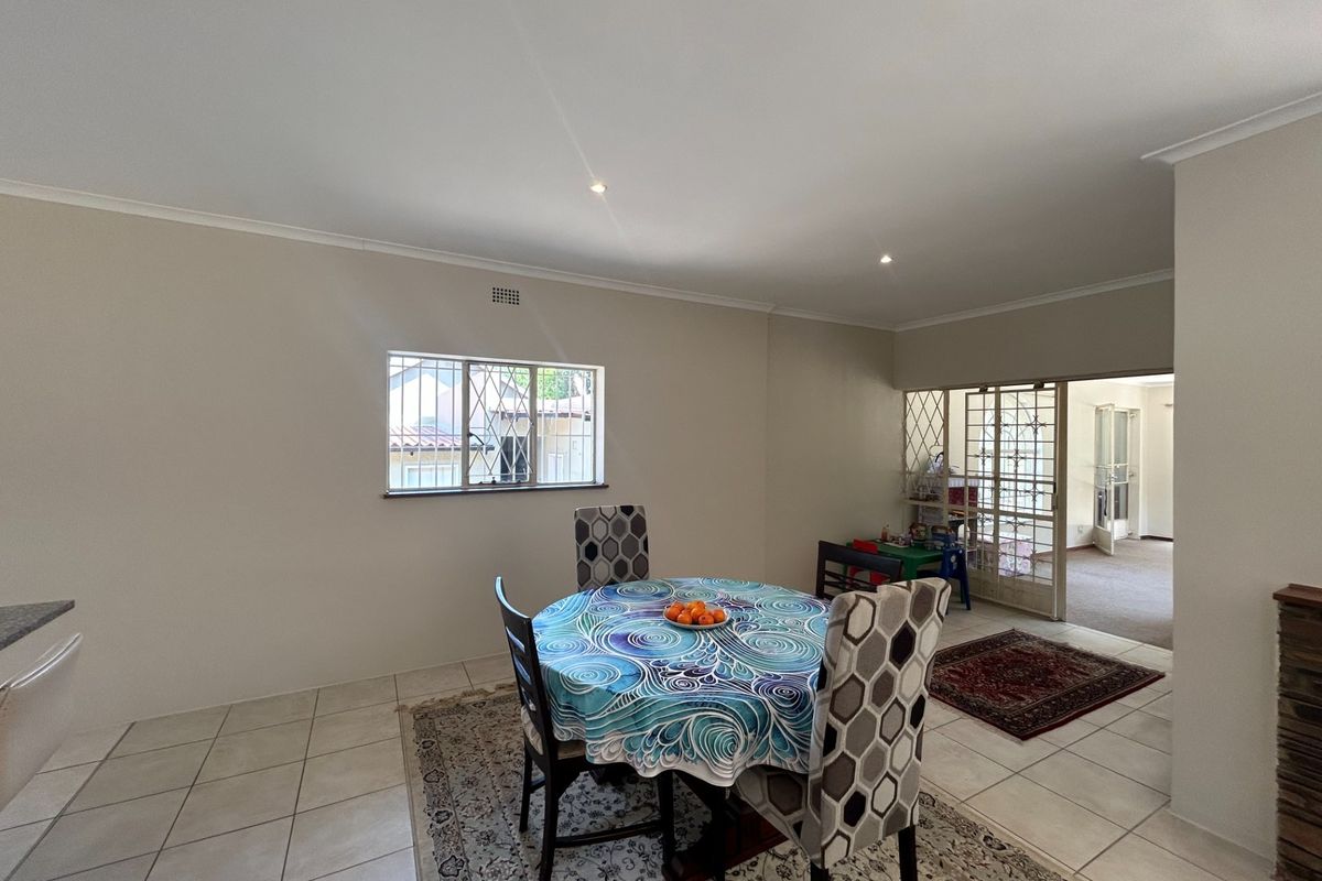 A neutrally painted living area featuring tiled flooring, recessed downlights, and a security gate leading to an adjacent room.