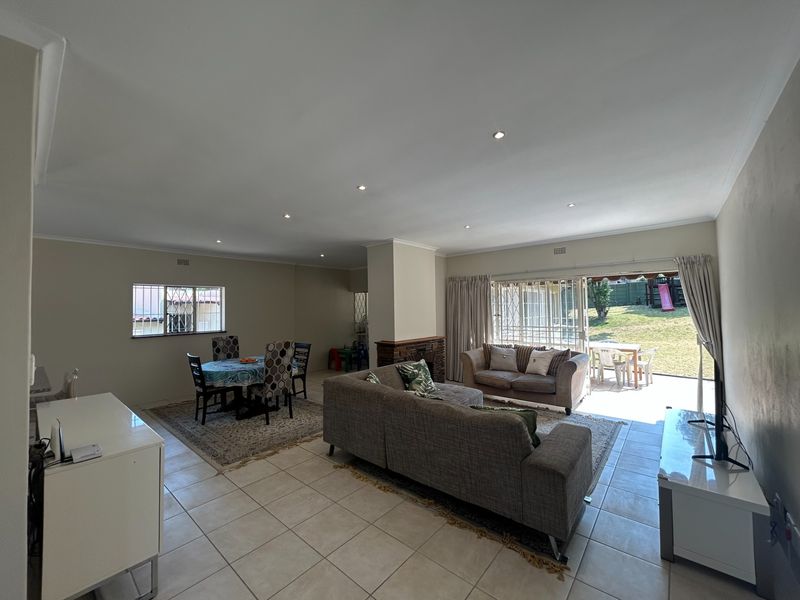 Spacious open-plan living and dining area featuring tiled floors, recessed lighting, and direct access to the rear garden through sliding glass doors.