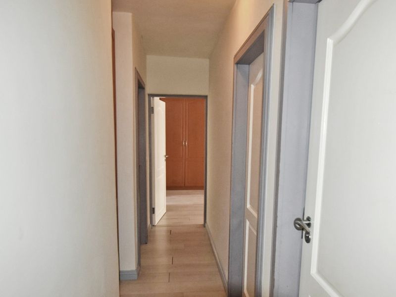 A functional hallway connecting multiple rooms, featuring neutral wall finishes, laminate flooring, and standard internal door frames.