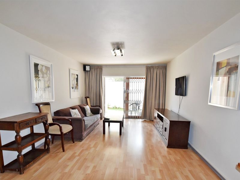 A well-lit living room featuring laminate flooring and a sliding glass door that provides access to the outdoor area.