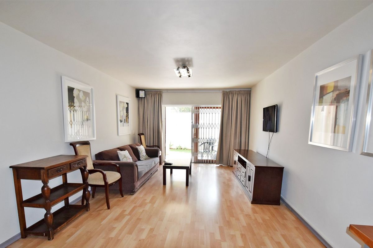 A well-lit living room featuring laminate flooring and a sliding glass door that provides access to the outdoor area.