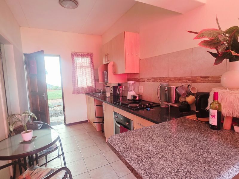 A functional kitchen featuring granite countertops, built-in cabinetry, and an integrated oven and hob, with direct access to the exterior.
