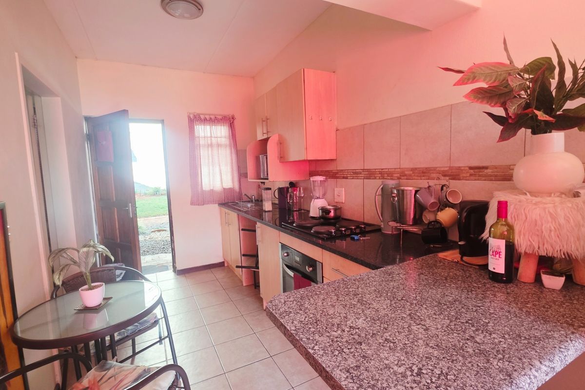 A functional kitchen featuring granite countertops, built-in cabinetry, and an integrated oven and hob, with direct access to the exterior.