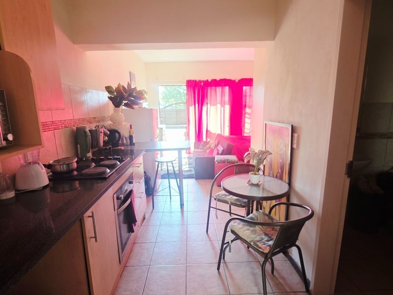 Open-plan kitchen and living area featuring tiled flooring, built-in cabinetry with granite countertops, and integrated cooking appliances.
