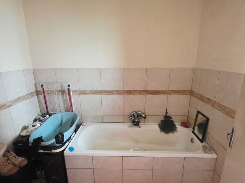 A functional bathroom featuring a built-in bathtub with tiled surround and a pedestal sink.