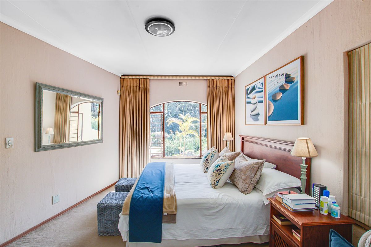 A well-maintained bedroom featuring an arched window, neutral wall tones, and carpeted flooring, providing a comfortable and inviting living space.