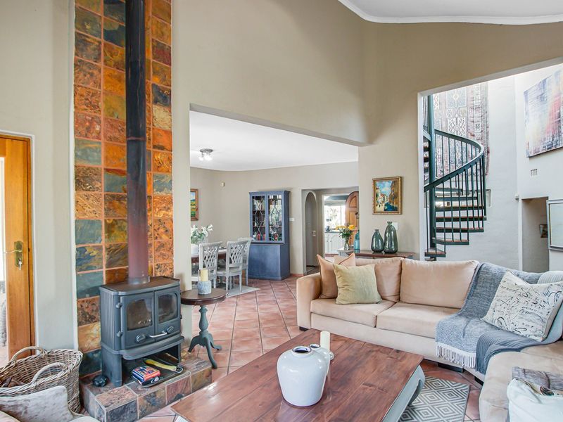 Spacious living area featuring a striking slate-tiled fireplace, terracotta flooring, vaulted ceilings, and a unique spiral staircase leading to an upper level.
