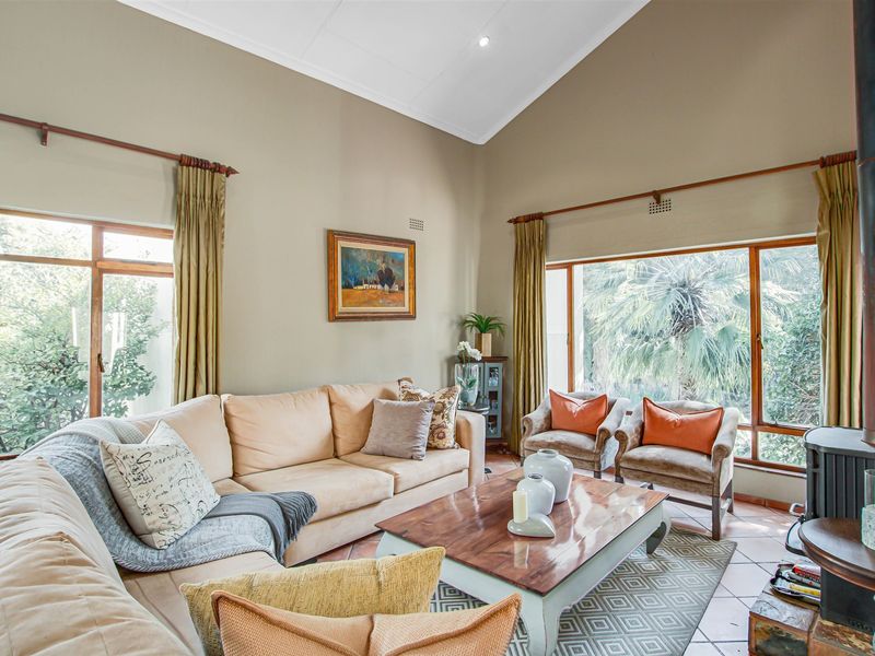 Spacious living room featuring a high vaulted ceiling, large windows providing natural light, and a built-in wood-burning fireplace with tiled flooring.