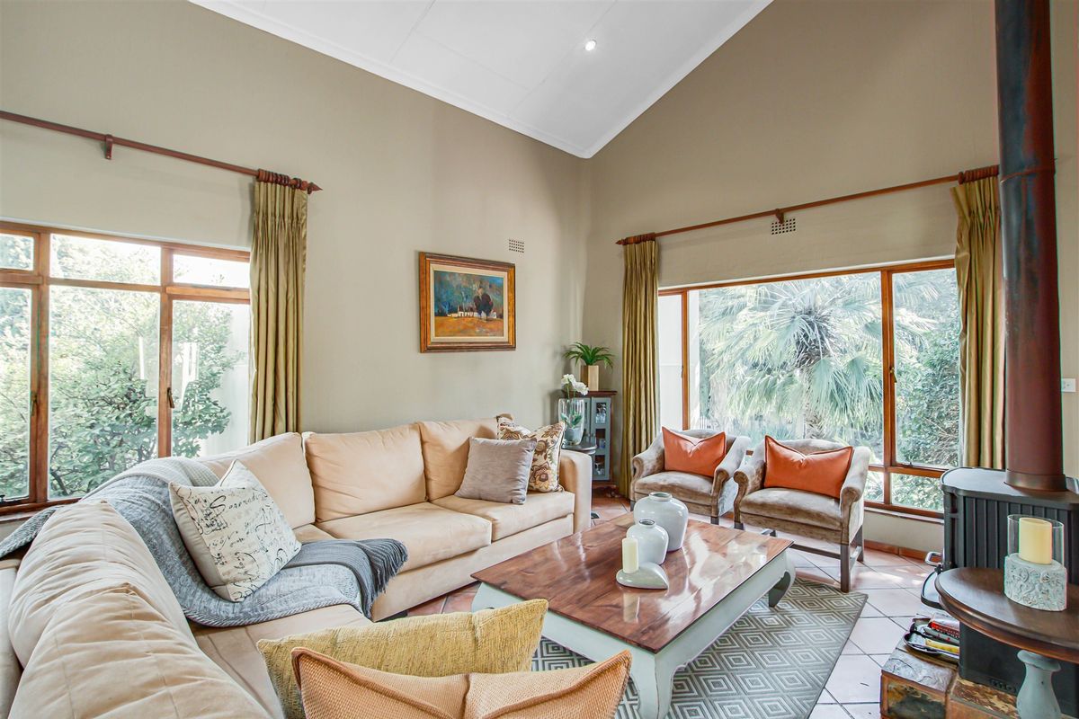 Spacious living room featuring a high vaulted ceiling, large windows providing natural light, and a built-in wood-burning fireplace with tiled flooring.