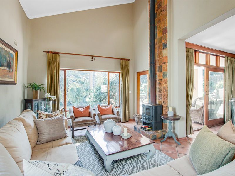 Spacious living room featuring a vaulted ceiling, terracotta floor tiles, and a prominent freestanding fireplace with a tiled hearth.