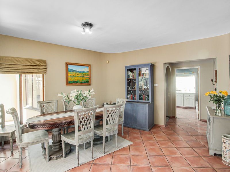 A dining room featuring terracotta floor tiles and an archway leading to an adjacent room, providing a functional and connected living space.